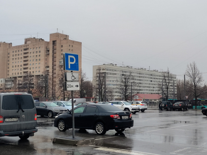 Парковочный знак и автомобили на открытой стоянке возле жилых домов