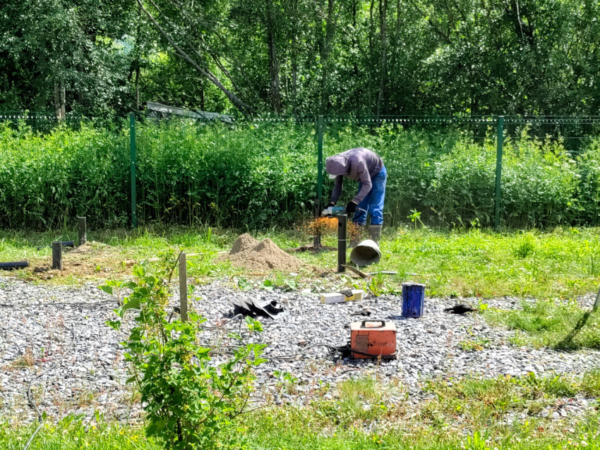 Искры при резке металлической трубы для свайного фундамента на щебёночной подсыпке
