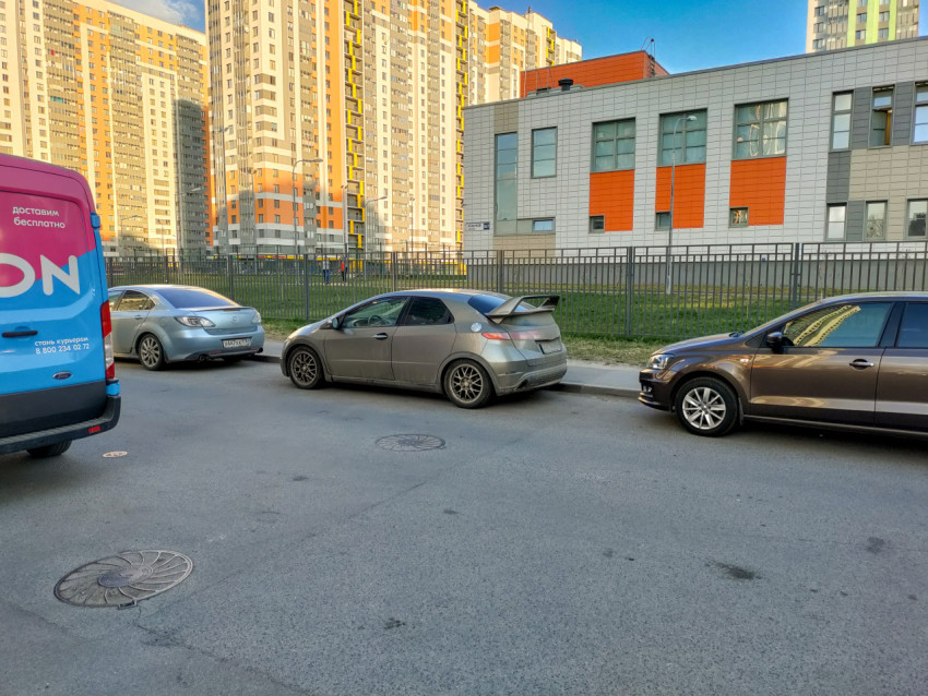 Припаркованные автомобили возле жилого дома и школы