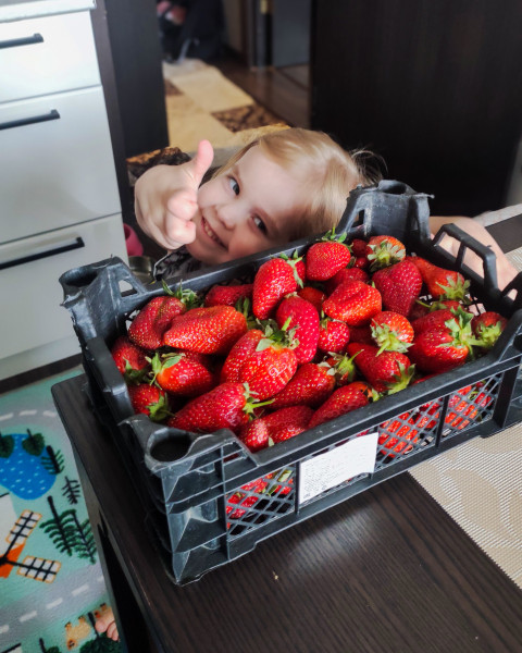 Ребенок с ящиком клубники и жестом «нравится»