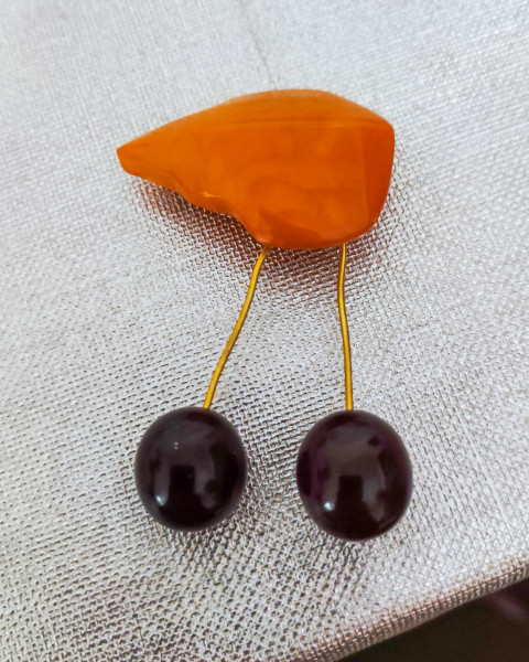 Брошь в виде вишни с двумя тёмными бусинами на ткани крупным планом