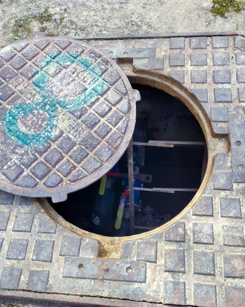 Открытый канализационный люк с коммуникациями