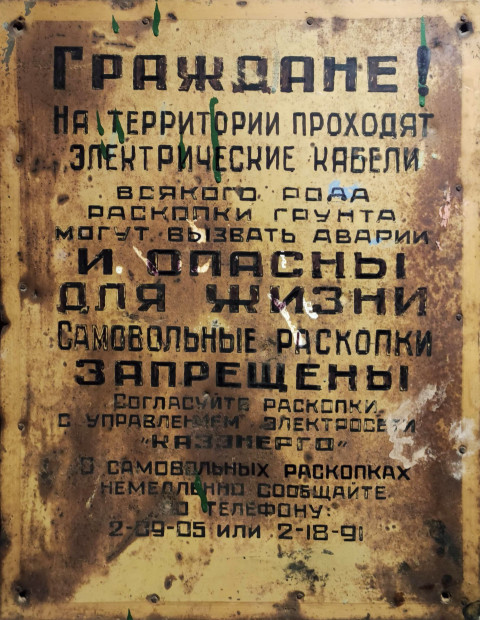 Старый металлический щит с предупреждением об электрических кабелях