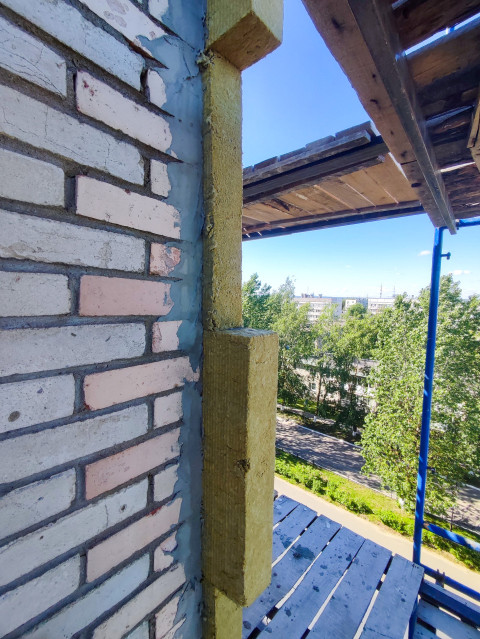 Утепление угла кирпичного здания минеральной ватой на строительных лесах