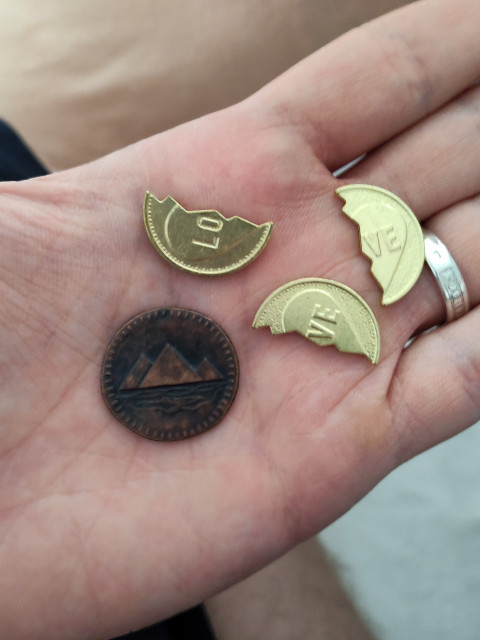 Монеты с надписью LOVE и жетон с пирамидой на ладони