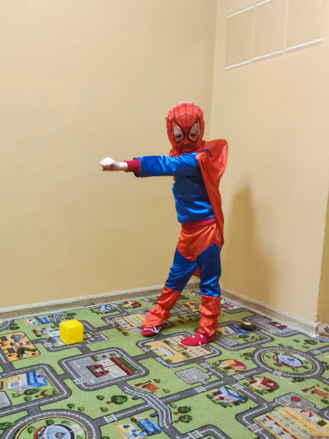 Ребенок в костюме супергероя в позе действия