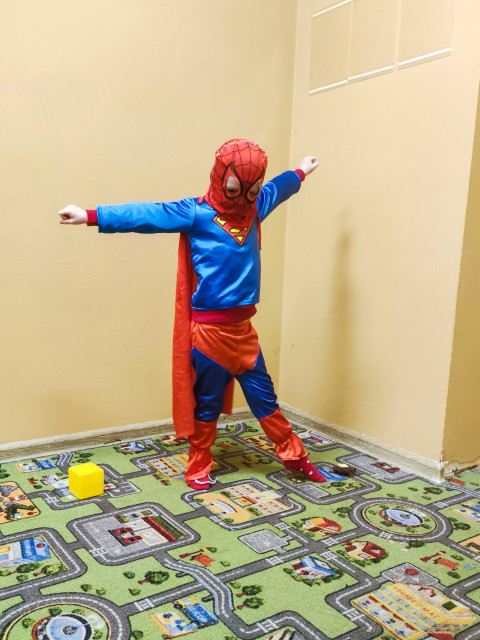 Ребенок в костюме супергероя с раскинутыми руками