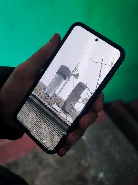 Мобильный телефон с увеличенным видом крыши жилого дома в зимний день