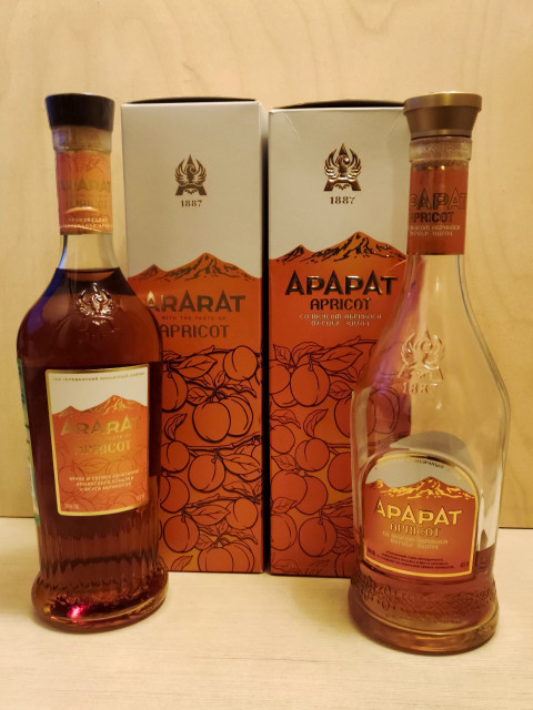 Упаковка и бутылки армянского коньяка Ararat Apricot на фоне дерева
