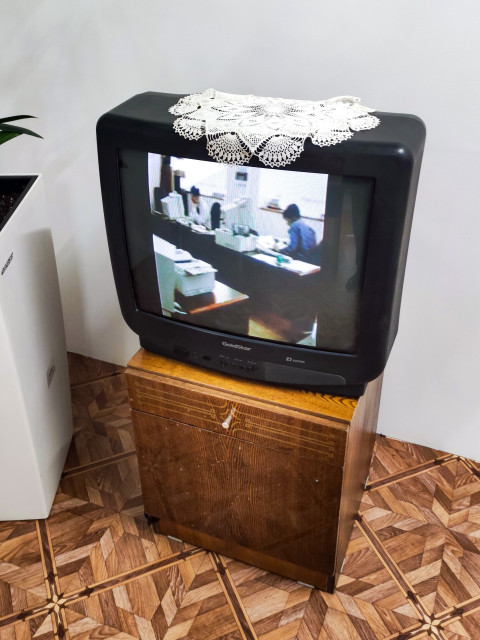 Телевизор GoldStar на тумбе с видеорядом офисной работы