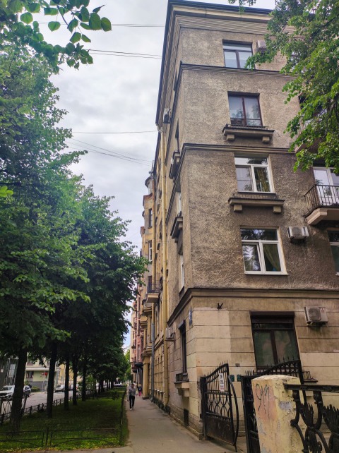 Тротуар вдоль жилого дома с деревьями, проводами и воротами