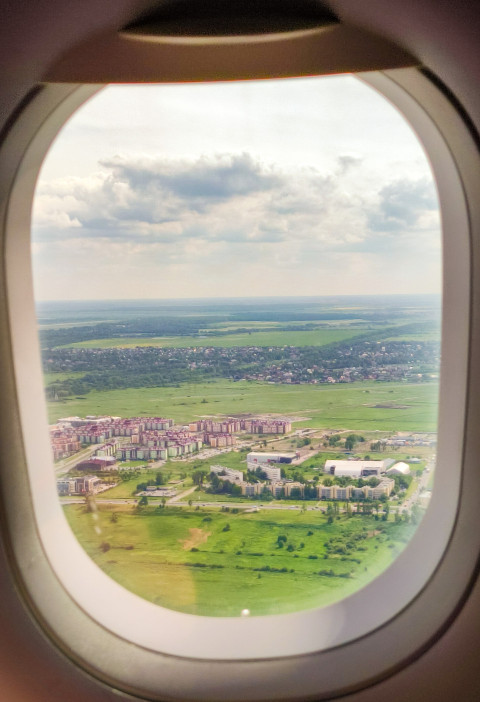 Вид из окна самолета на зеленые поля и город