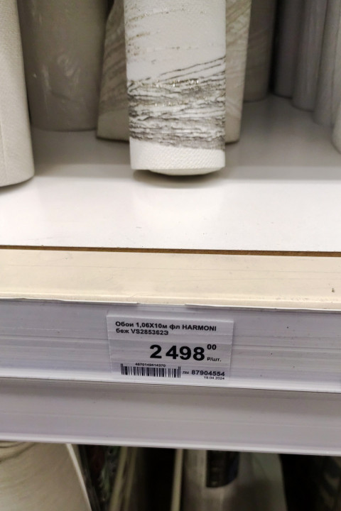 Ценник и рулоны обоев HARMONI на полке магазина