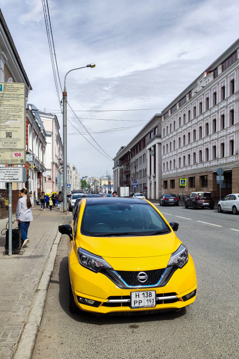 Жёлтый Nissan Note на обочине городской улицы