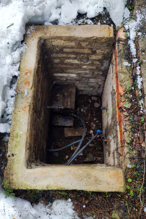 Колодец с инженерными коммуникациями в снегу