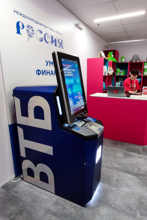 Банкомат ВТБ на фоне стенда «Умные финансы» выставки «Россия»