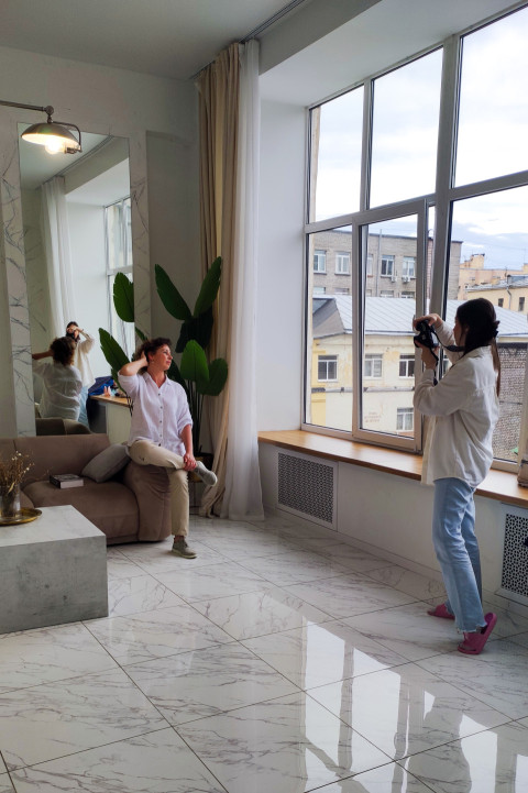 Женщина позирует на диване у окна во время фотосессии