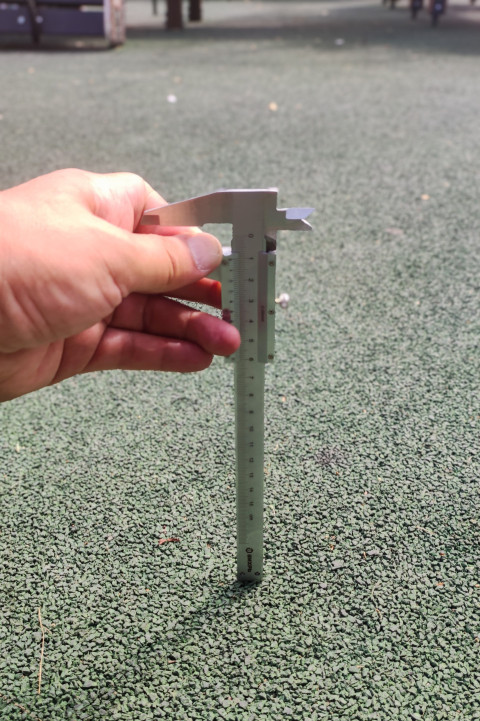 Штангенциркуль с маркировкой «ВИХРЬ» на фоне резиновой крошки, вертикальный кадр