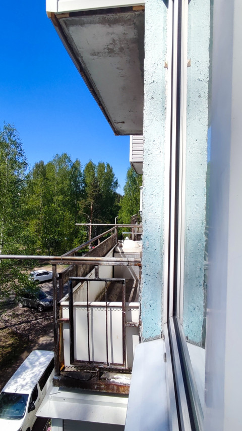 Балкон многоэтажного дома с видом на деревья и двор