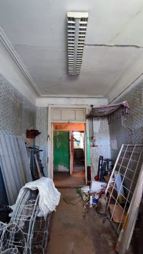 Комната с повреждённым потолком и строительным мусором