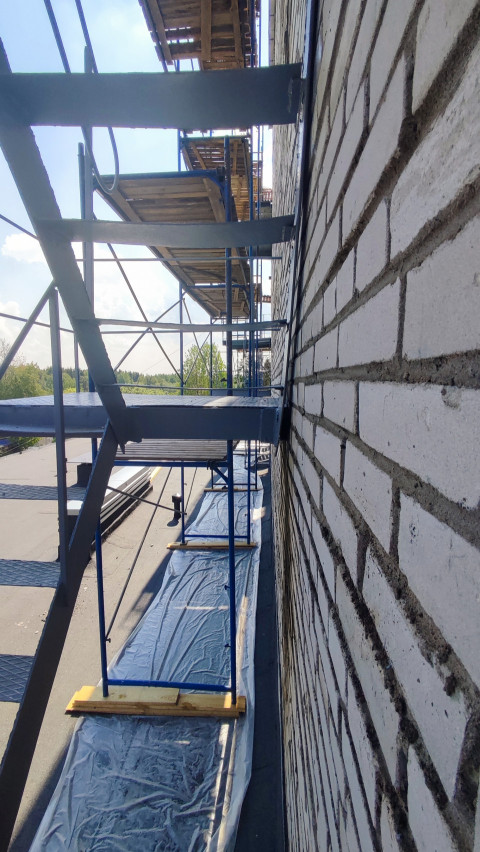 Строительные леса вдоль кирпичной стены на крыше здания