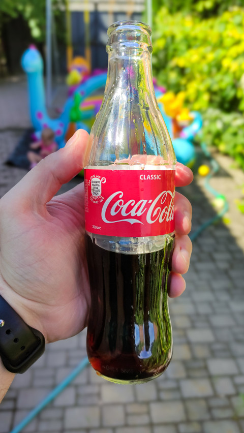 Бутылка Coca-Cola в руке крупным планом