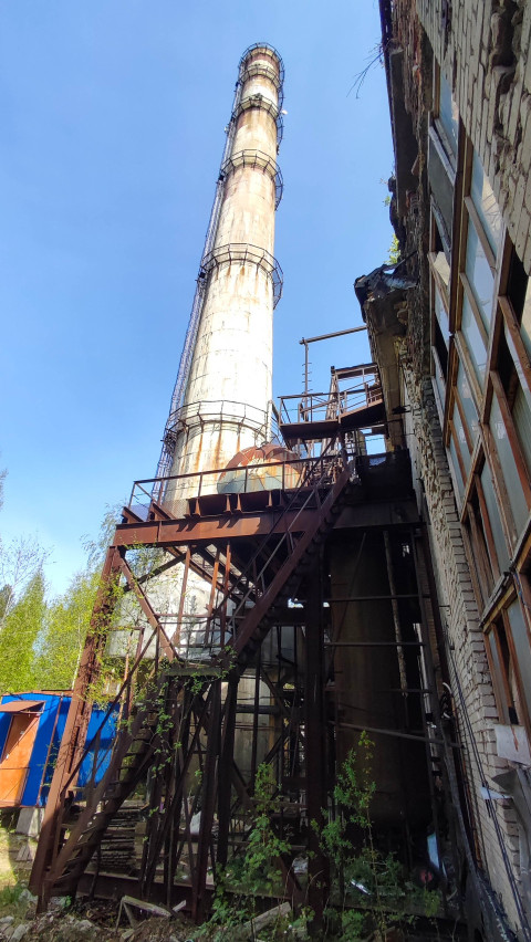 Промышленная труба на заброшенном заводе с ярким небом