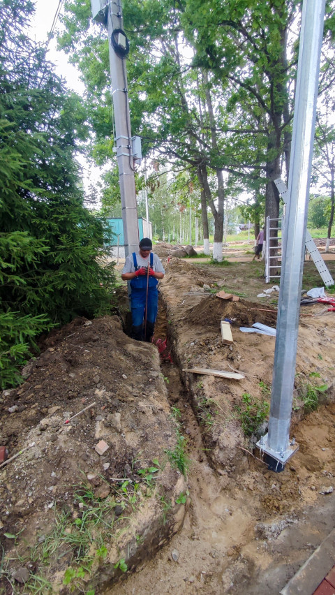 Рабочий в траншее при монтаже кабельных коммуникаций