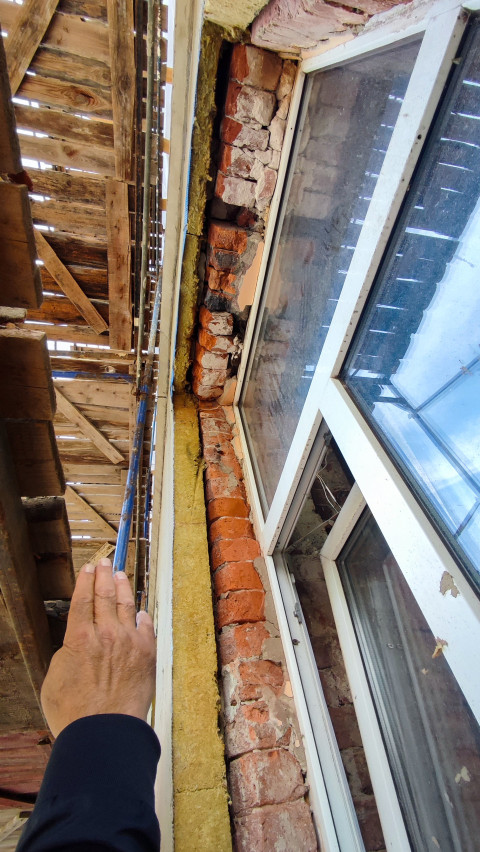 Участок кирпичной стены с утеплителем и оконным проёмом под ремонтом