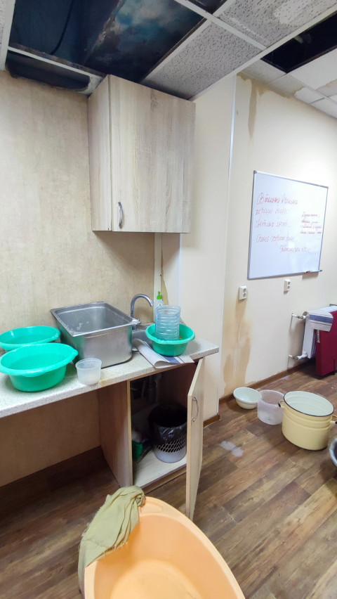 Кухонная зона с поврежденным потолком и емкостями для сбора воды