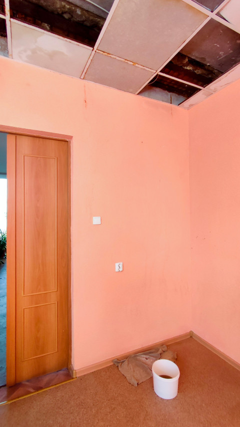 Потолок с поврежденными плитами и ведром для сбора воды