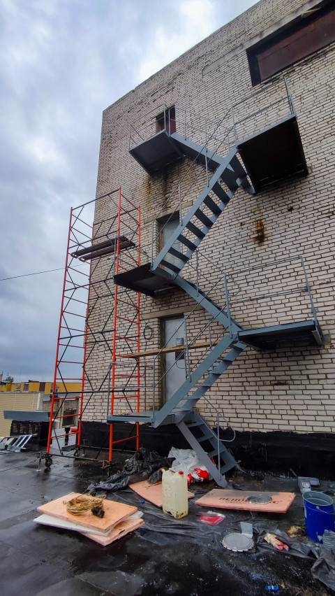 Кирпичное здание с пожарной лестницей и строительными лесами