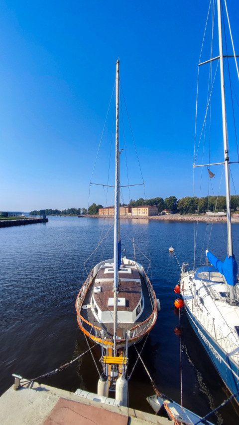 Парусная яхта у причала на фоне берега