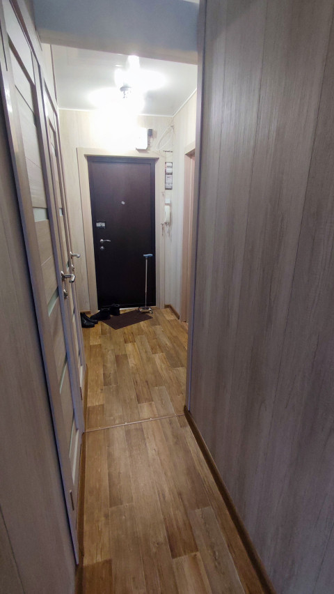 Освещённый коридор квартиры после ремонта с деревянной отделкой