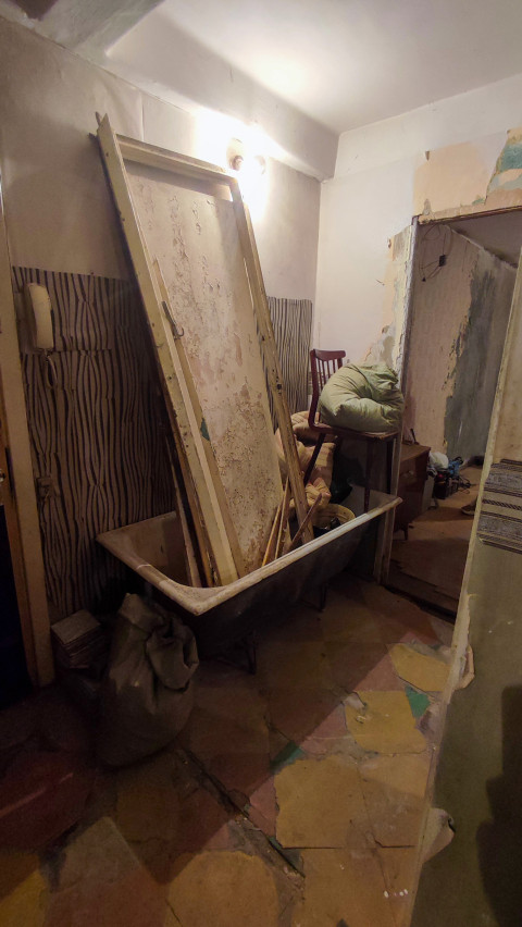 Ванна с демонтированными дверями и строительными отходами в квартире перед ремонтом