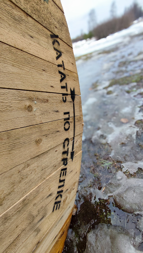 Надпись «Катать по стрелке» на деревянной катушке вертикально