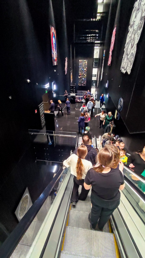 Посетители на эскалаторе, спускающемся в подземный уровень павильона «Атом»