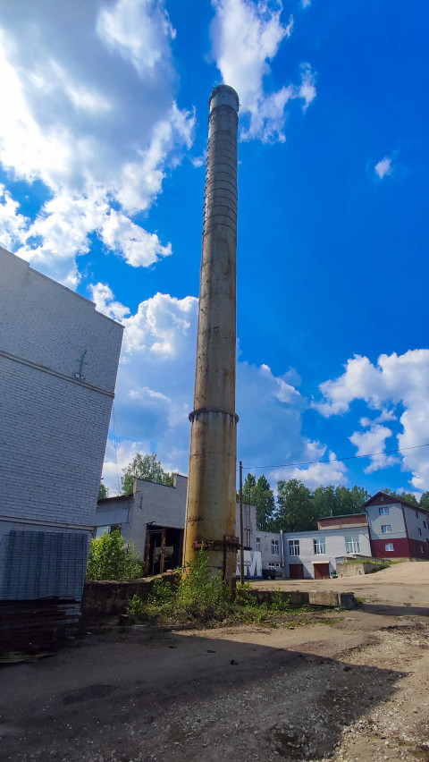 Металлическая дымовая труба на территории промзоны