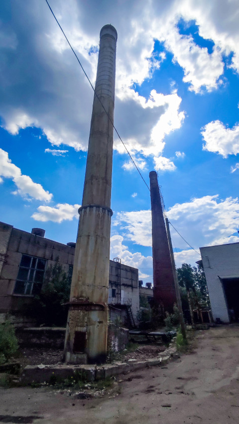 Две высокие дымовые трубы у промышленных зданий