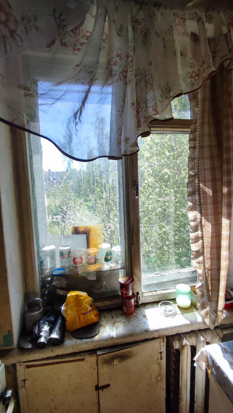 Окно кухни с банками, продуктами и шторой