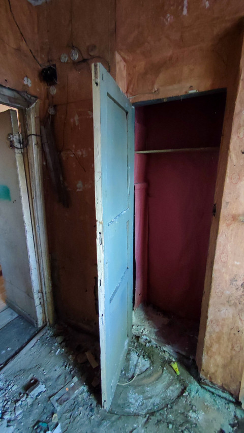 Открытый шкаф и разрушенная стена в старом помещении