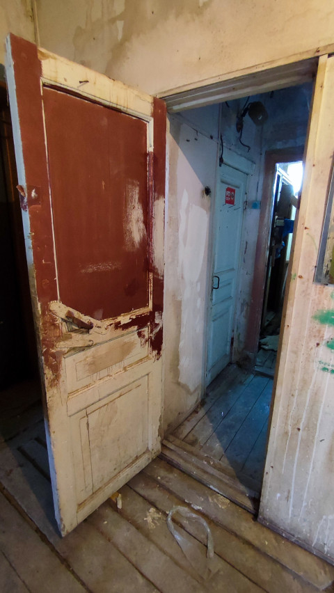 Проём с повреждённой дверью в старом коридоре