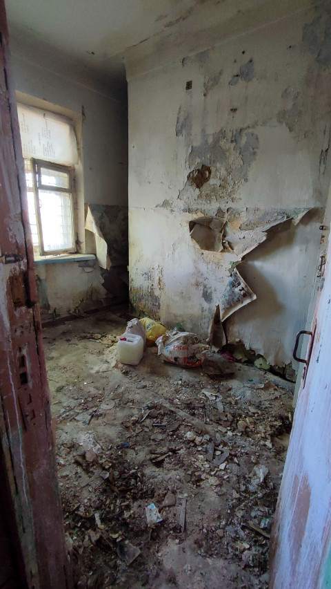 Комната с разрушенными стенами и мусором на полу