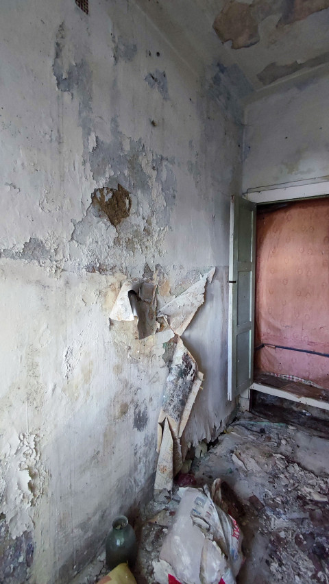 Стена с многочисленными повреждениями и открытым проёмом в соседнее помещение