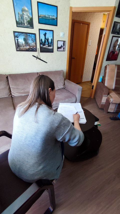 Женщина за столом заполняет документы в жилой комнате