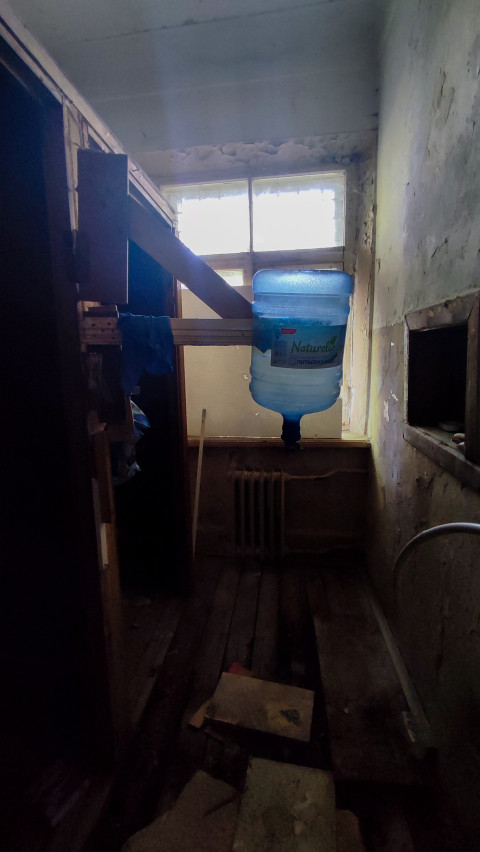 Емкость для воды и разрушенные стены в узкой комнате