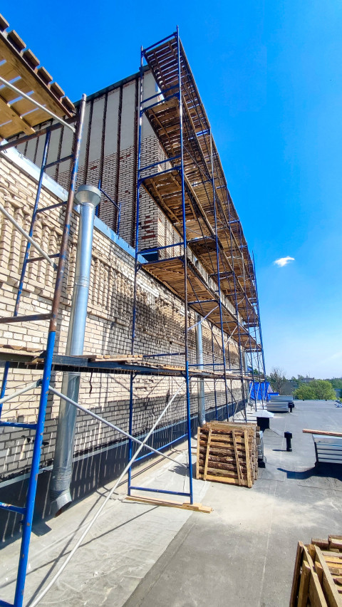 Строительные леса вдоль кирпичной стены здания