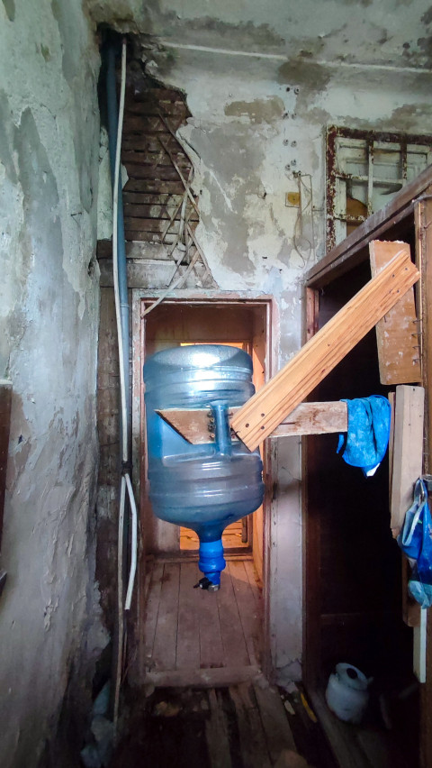 Коридор с подвешенной бутылью для воды, деревянным кронштейном и проломом в полу