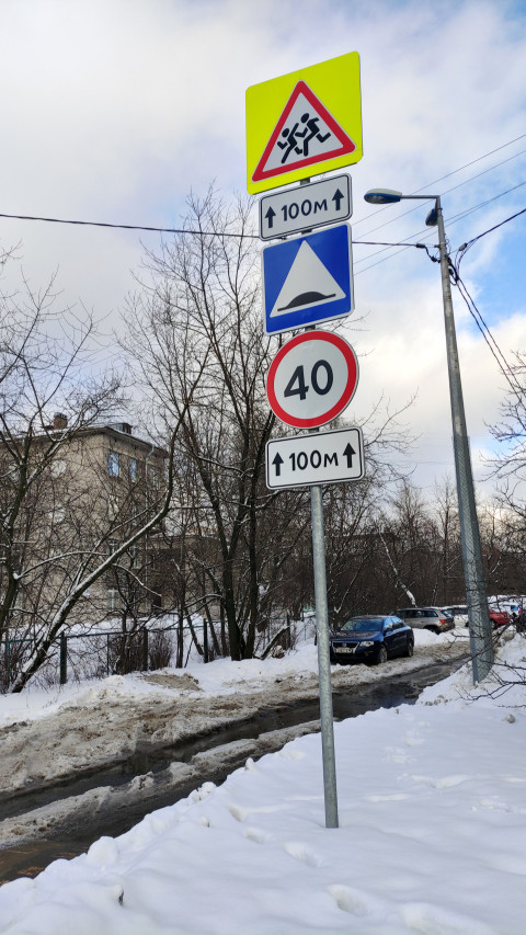 Дорожные знаки на обочине заснеженной дороги