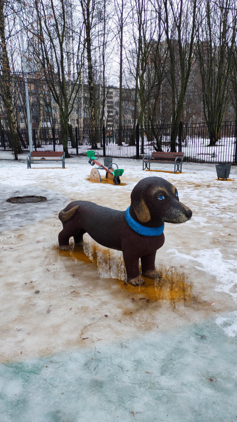 Фигура собаки в зимнем парке на фоне деревьев и снежной площади
